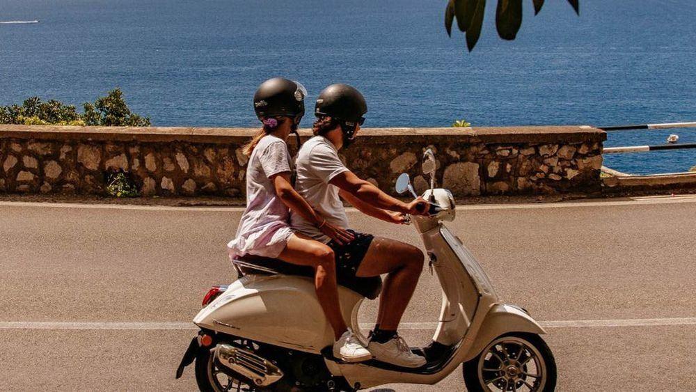 Couple riding a scooter along the coast road